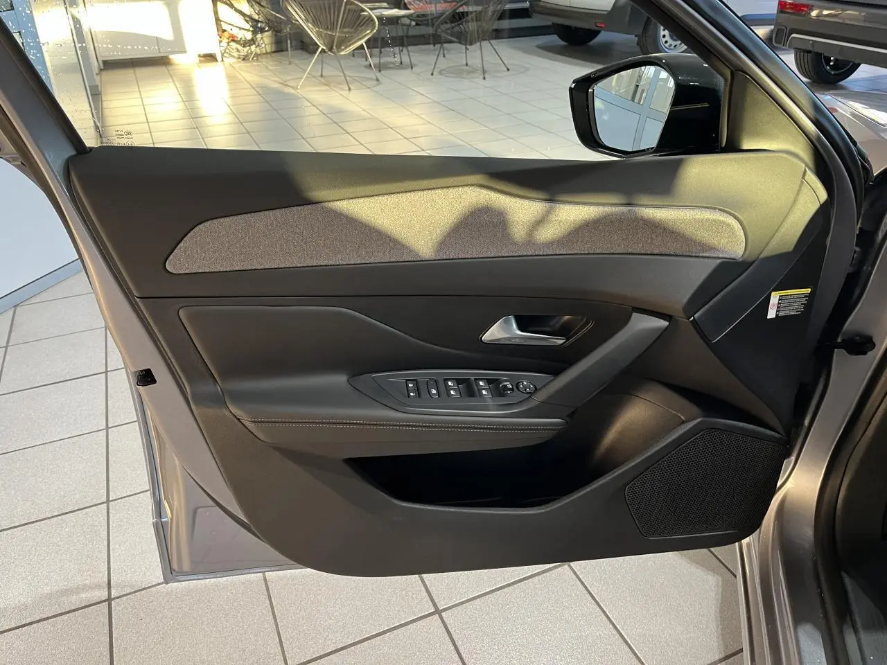 Vue intérieure de la porte côté conducteur de la Peugeot 308 SW 2024 en gris clair Metal Artense avec commandes électriques.