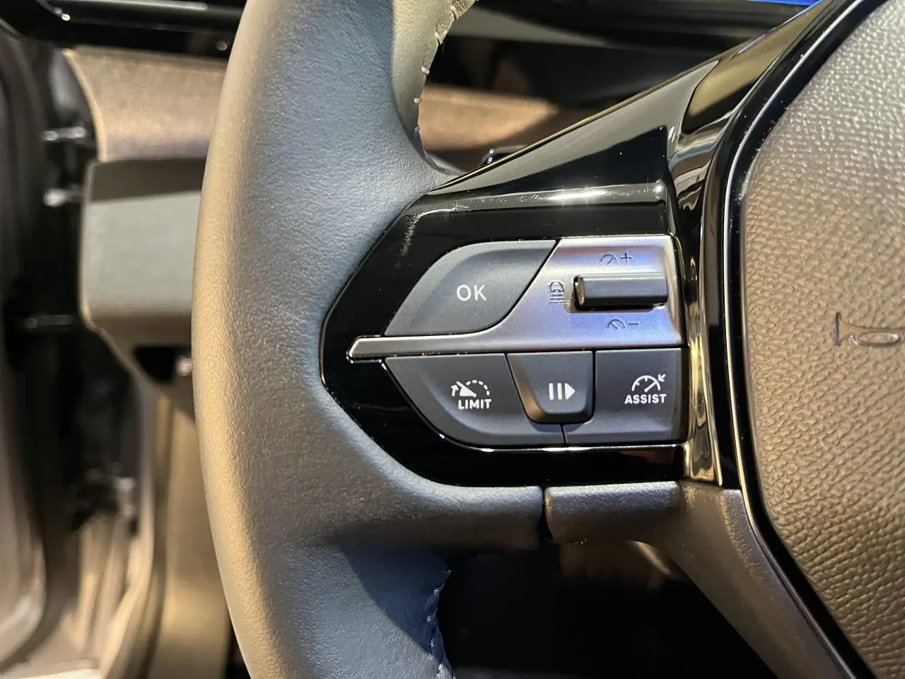 Gros plan sur les commandes à gauche du volant noir du Peugeot 308 SW gris clair Metal Artense 2024.