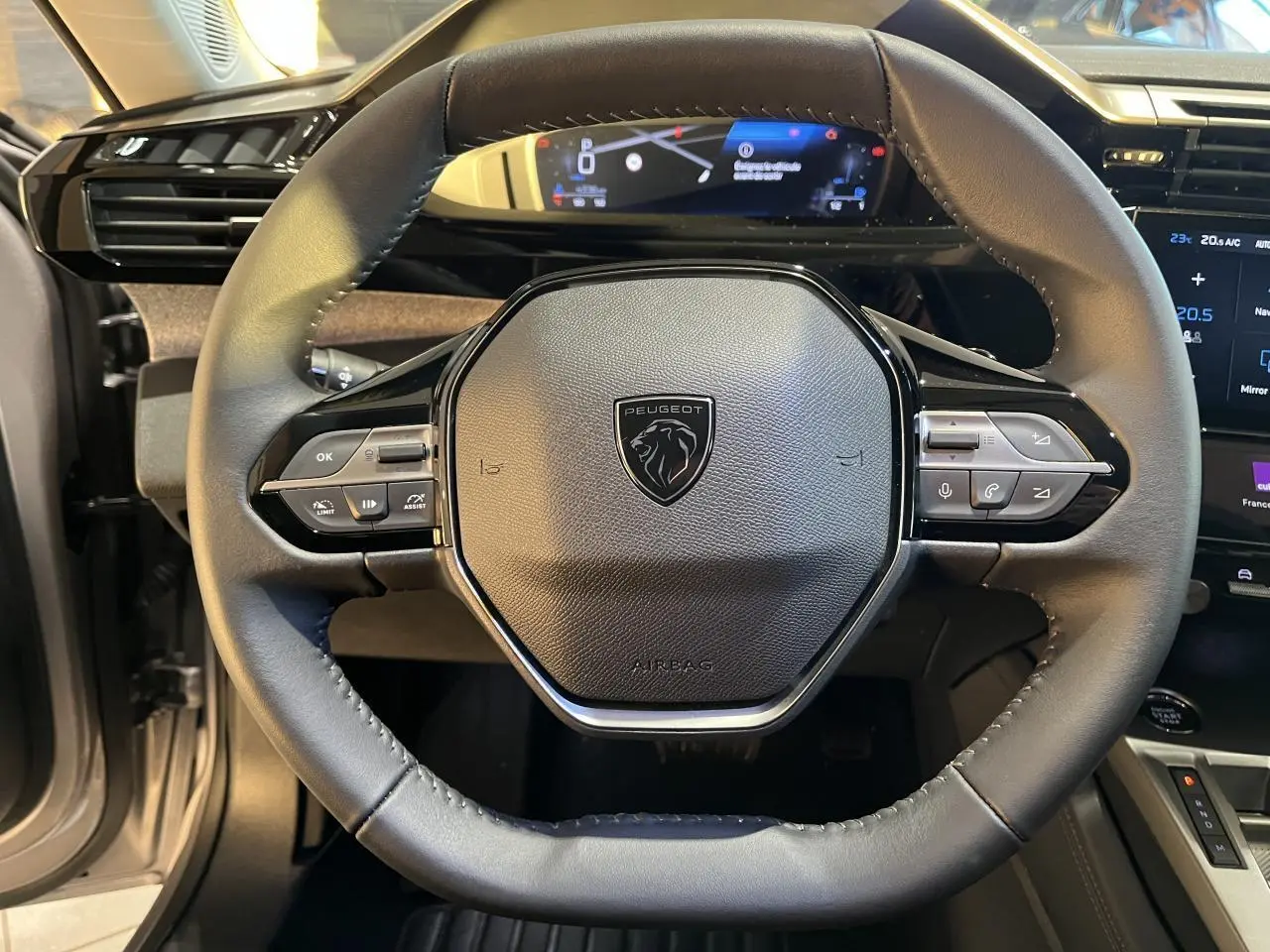 Vue rapprochée du volant cuir noir de la Peugeot 308 SW 2024 avec commandes intégrées et tableau de bord numérique.