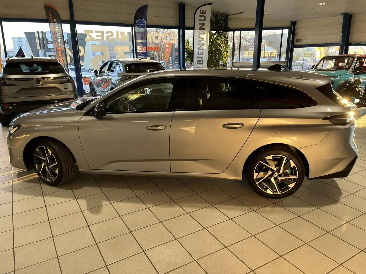 Peugeot 308 SW gris clair métallisé vue de profil côté gauche en intérieur avec jantes alliage distinctives.