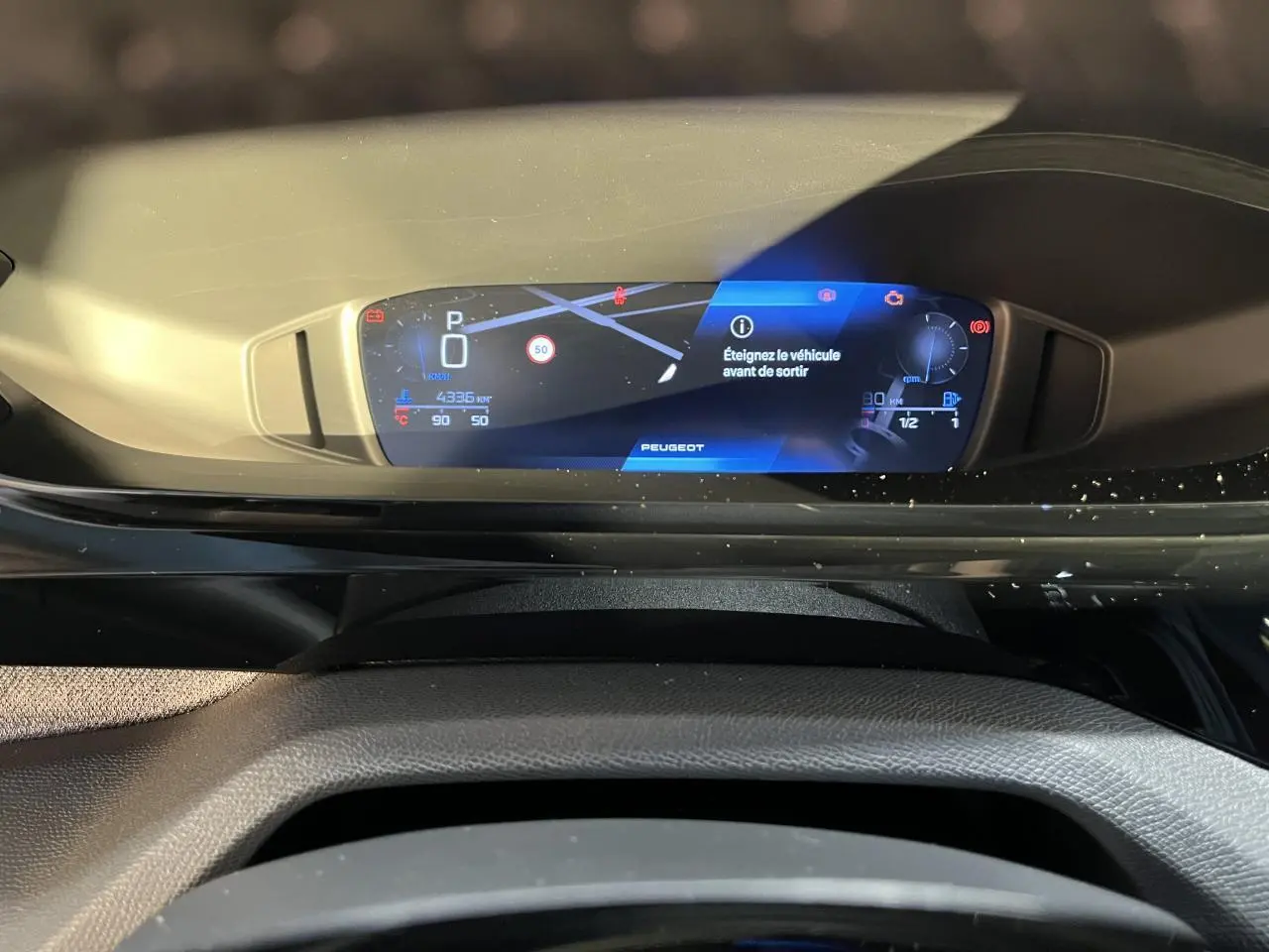 Tableau de bord numérique du Peugeot 308 SW 2024 affichant la navigation et alertes, vue intérieure frontale.