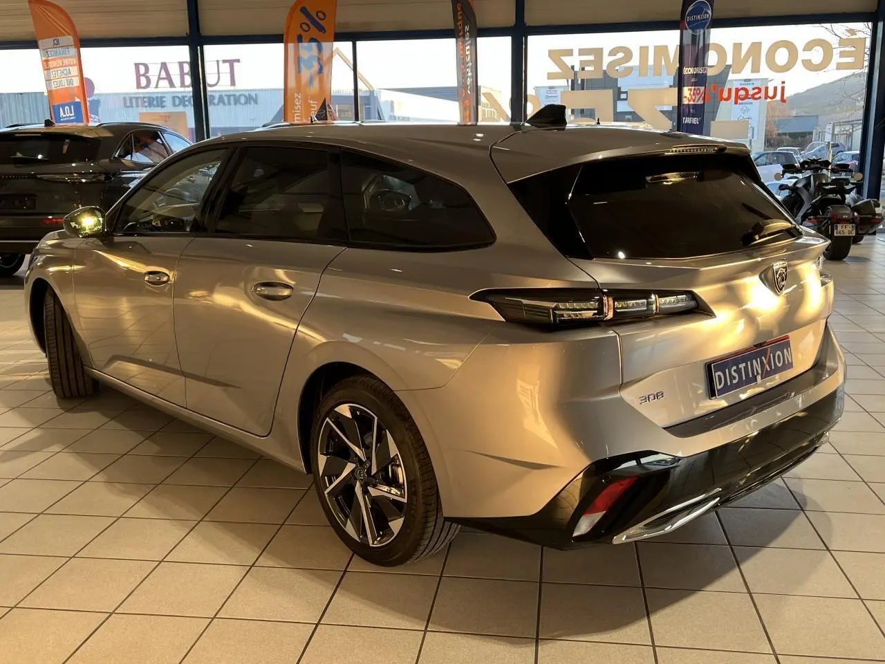 Peugeot 308 SW gris clair Metal Artense vue 3/4 arrière droit en showroom avec jantes alliage distinctives.
