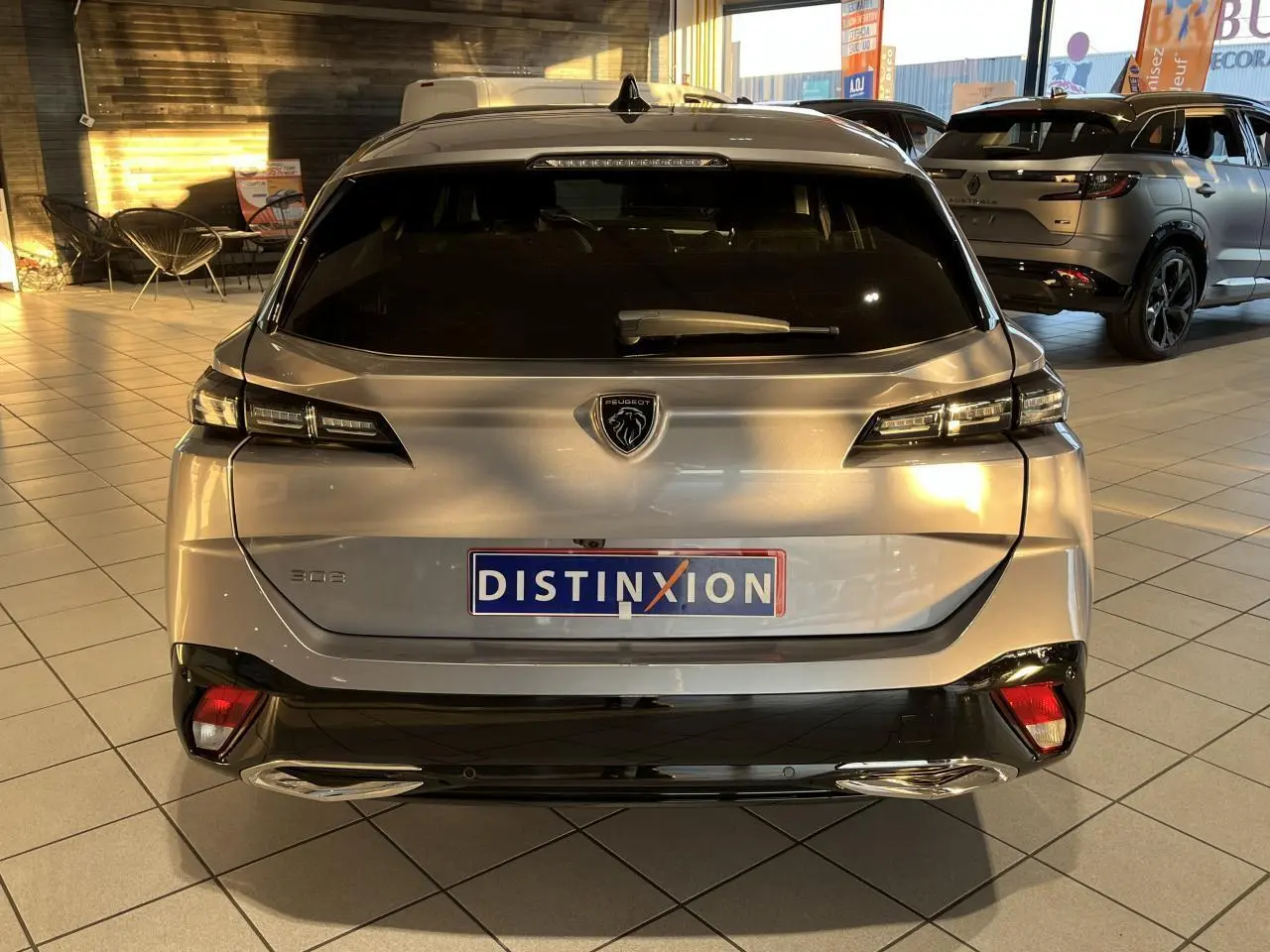 Vue arrière d'un Peugeot 308 SW gris clair Metal Artense avec feux LED et double sortie d'échappement chromée en showroom.