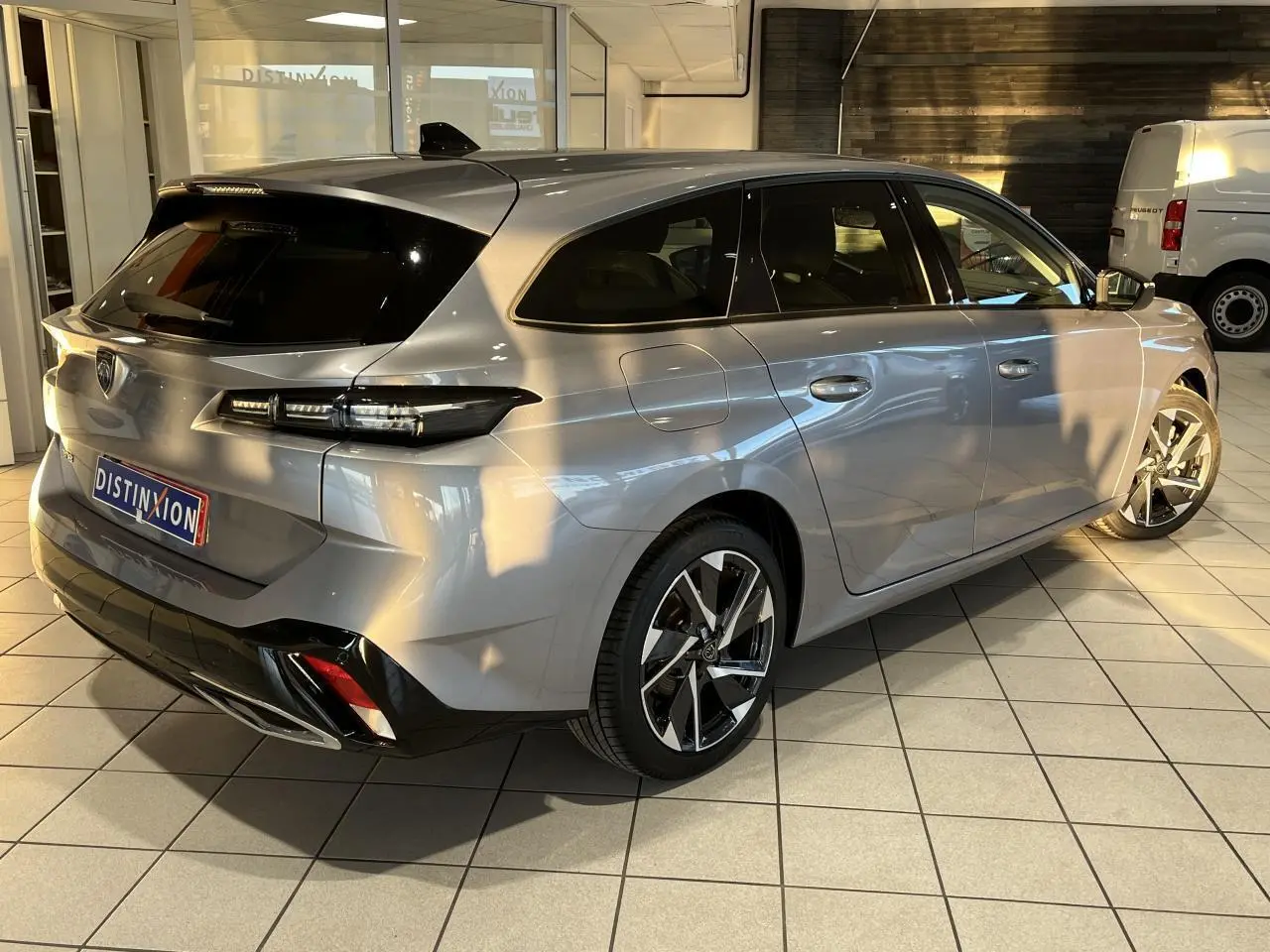 Peugeot 308 SW gris clair Metal Artense vue 3/4 arrière droit, avec jantes alliage et feux arrière LED distinctifs.