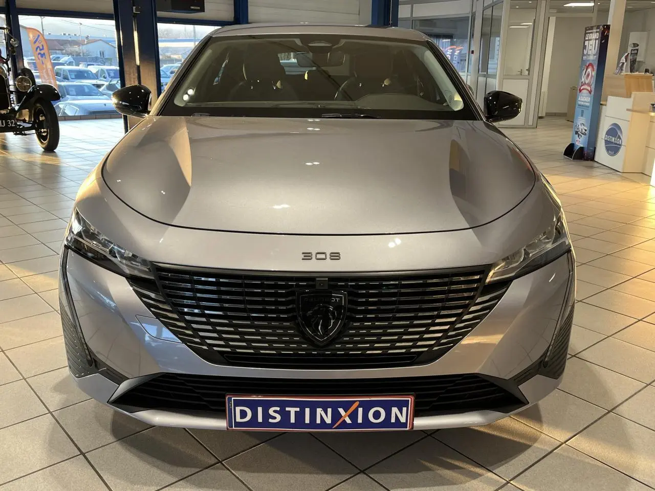 Vue frontale d'une Peugeot 308 SW gris clair Metal Artense 2024 avec calandre noire et logo lion central.