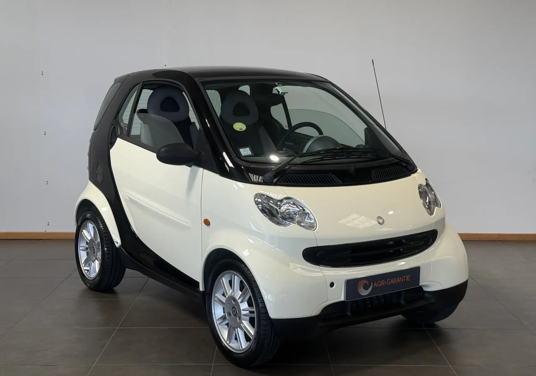Vue 3/4 avant d'une Smart Fortwo Coupé beige 2004 avec toit noir et jantes alliage argentées.