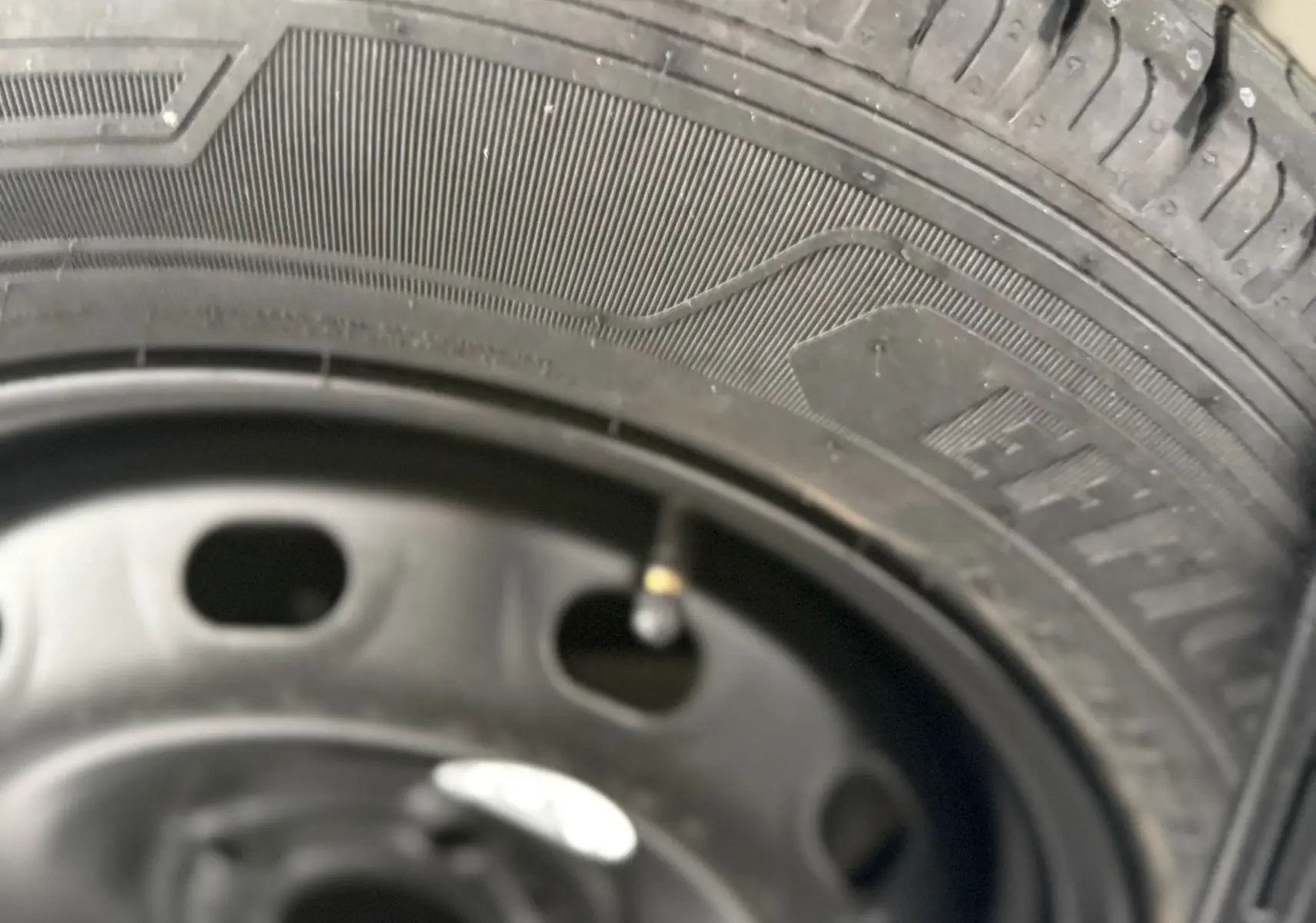 Gros plan sur la roue de secours noire du Renault Trafic Combi gris urbain, montrant le pneu et la jante acier.