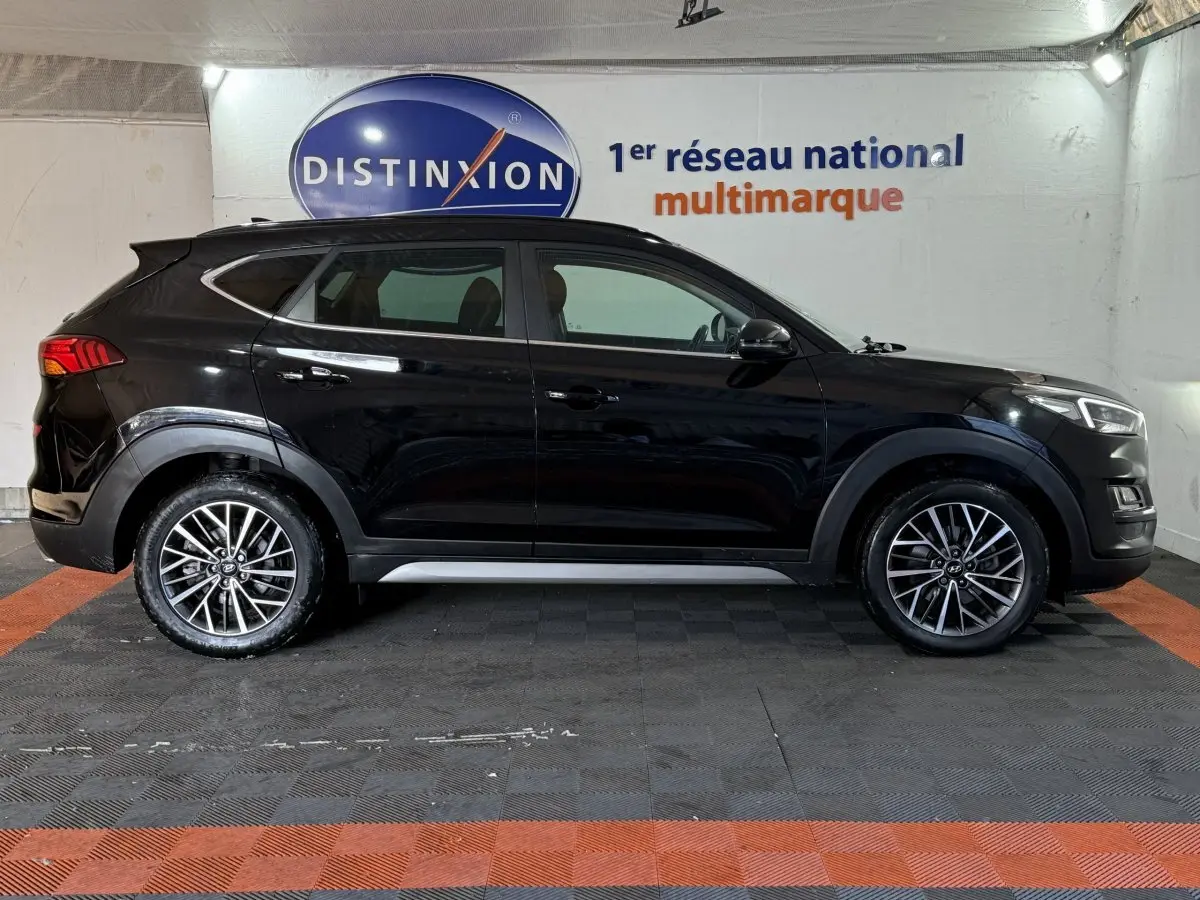 Vue latérale droite d’un Hyundai Tucson noir 2019 avec jantes alliage et rails de toit noirs dans un garage.