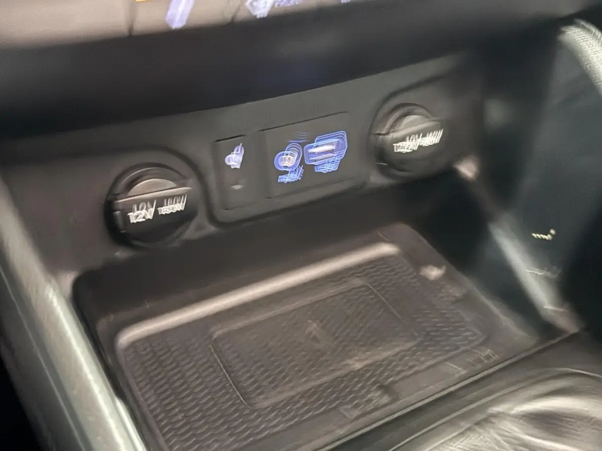 Gros plan sur la console centrale noire du Hyundai Tucson 2019, montrant prises 12V et commandes éclairées.
