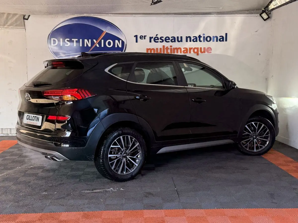 Vue 3/4 arrière droite d’un Hyundai Tucson noir 2019 avec jantes alliage et feux arrière LED visibles.