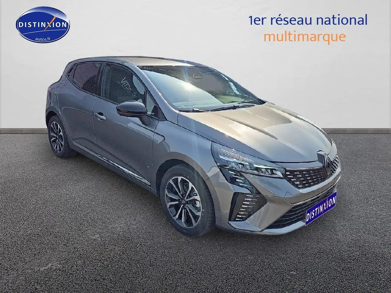 Renault Clio V gris schiste en 3/4 avant droit, avec calandre chromée et jantes alliage distinctives.