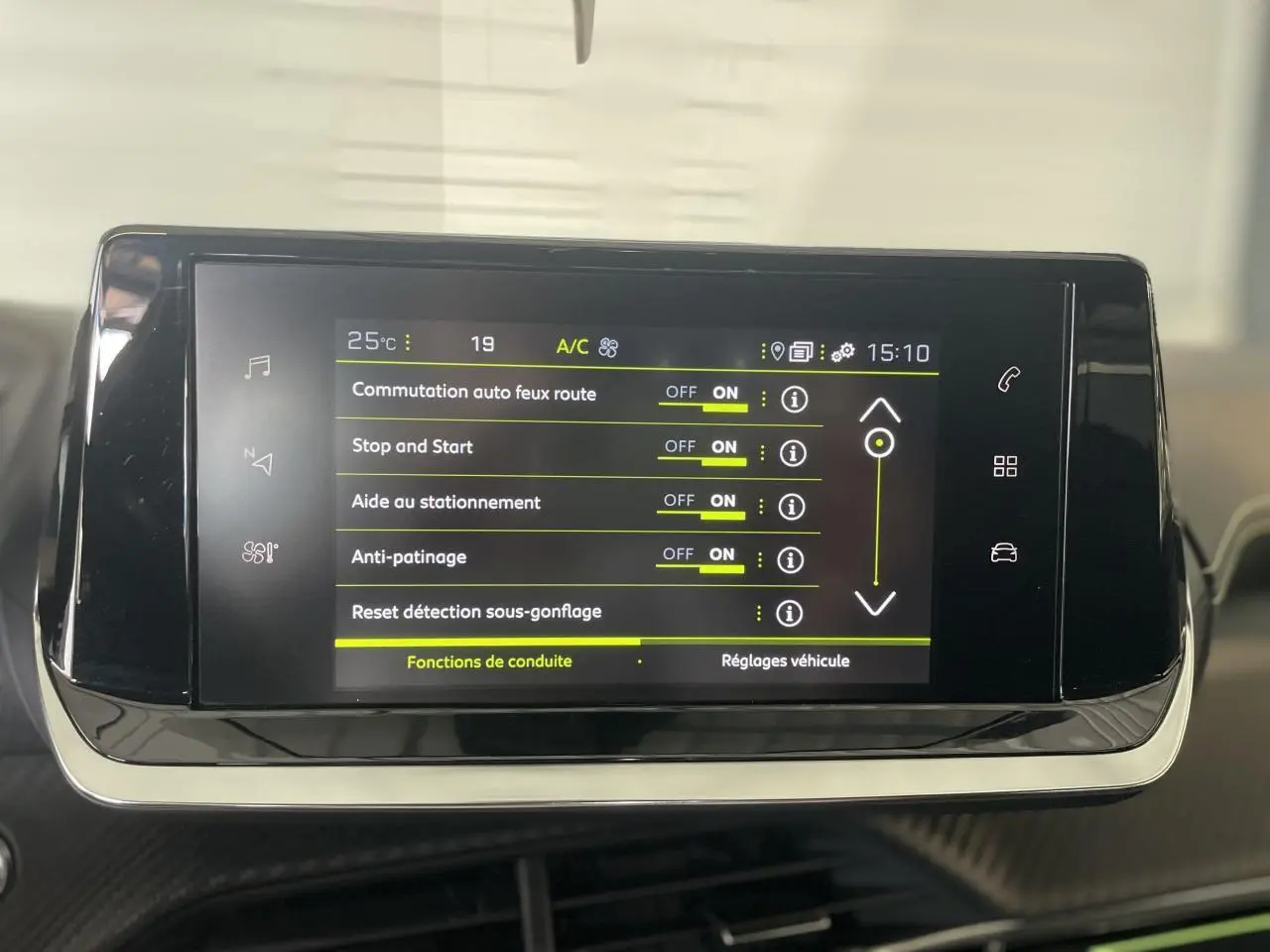 Écran tactile central affichant les réglages de conduite du Peugeot 208 gris clair, intérieur noir avec détails verts.