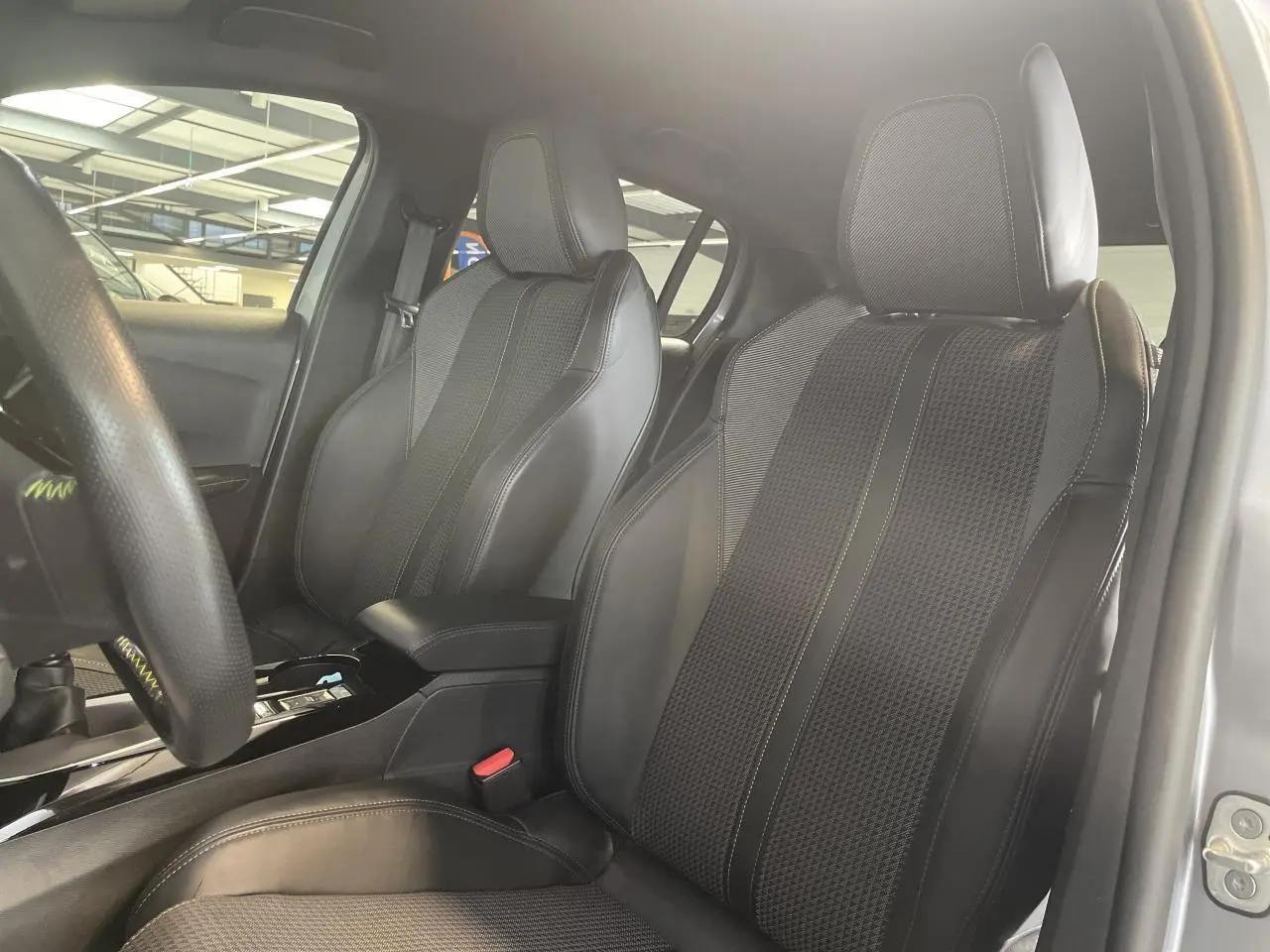 Gros plan sur les sièges avant en tissu et cuir noir de la Peugeot 208 gris clair métallisé, vue côté gauche intérieur.