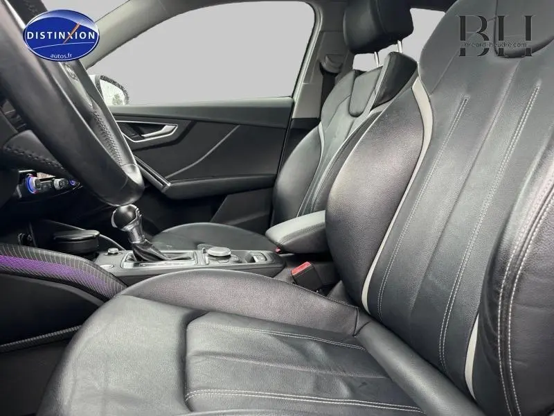 Vue intérieure côté conducteur de l'Audi Q2 2018 avec sièges cuir noir et console centrale équipée.