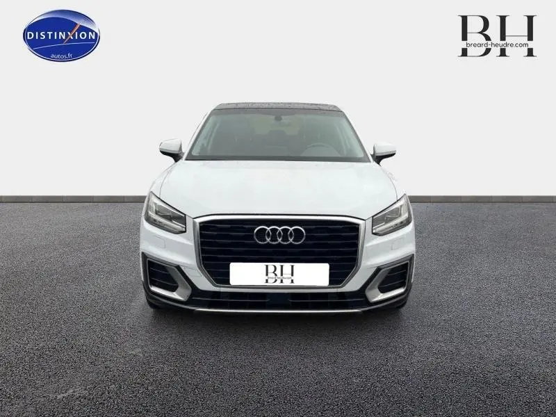Audi Q2 blanc Ibis vue de face avec calandre noire et phares LED distinctifs sur sol gris.