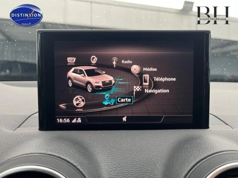 Écran central de l'Audi Q2 blanc Ibis affichant le menu multimédia avec navigation, radio et téléphone.