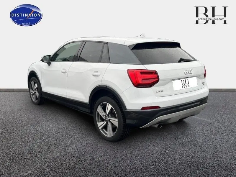 Audi Q2 blanc Ibis vue 3/4 arrière côté gauche avec toit noir et jantes alu 18 pouces style dynamique.