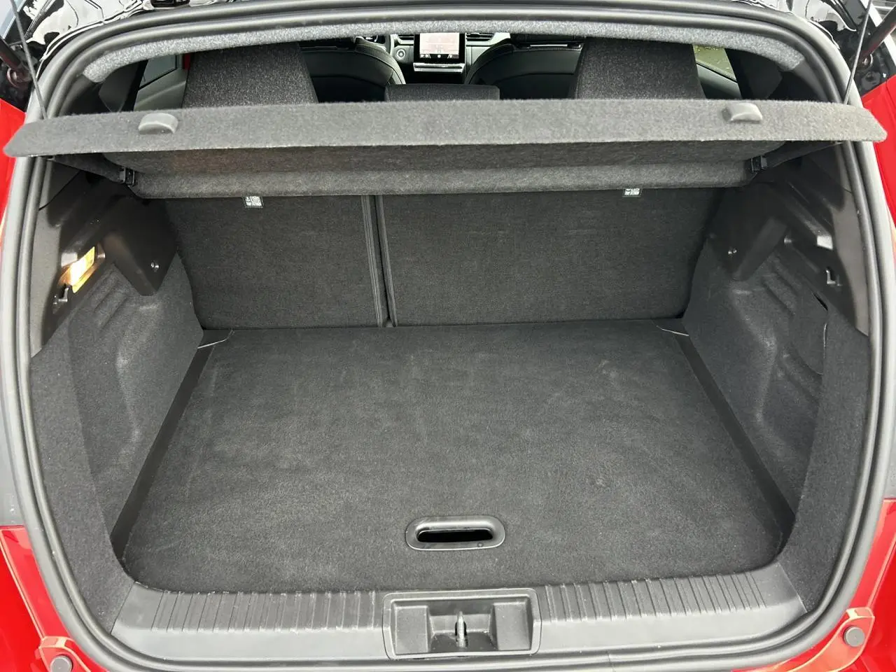 Vue arrière du coffre ouvert du Renault Captur 2025 Rouge Flamme avec intérieur noir et plancher plat.