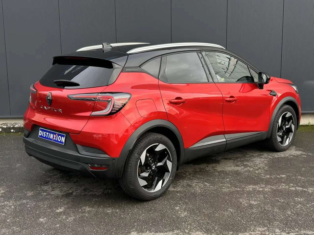 Renault Captur 2025 rouge Flamme et noir, vue 3/4 arrière droit, jantes alu noires diamantées et toit noir.