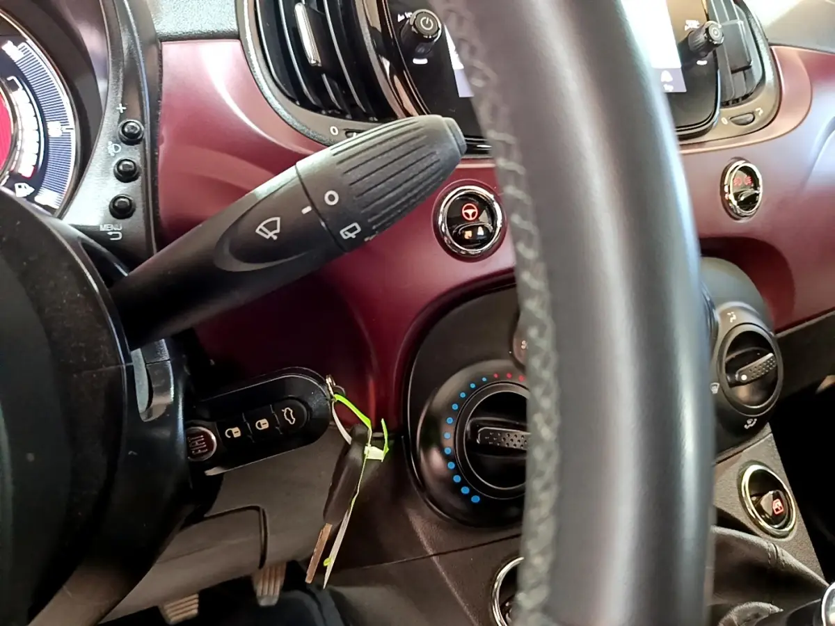 Vue intérieure rapprochée du tableau de bord rouge et du volant cuir de la Fiat 500 1.0 70ch BSG Star 2021.