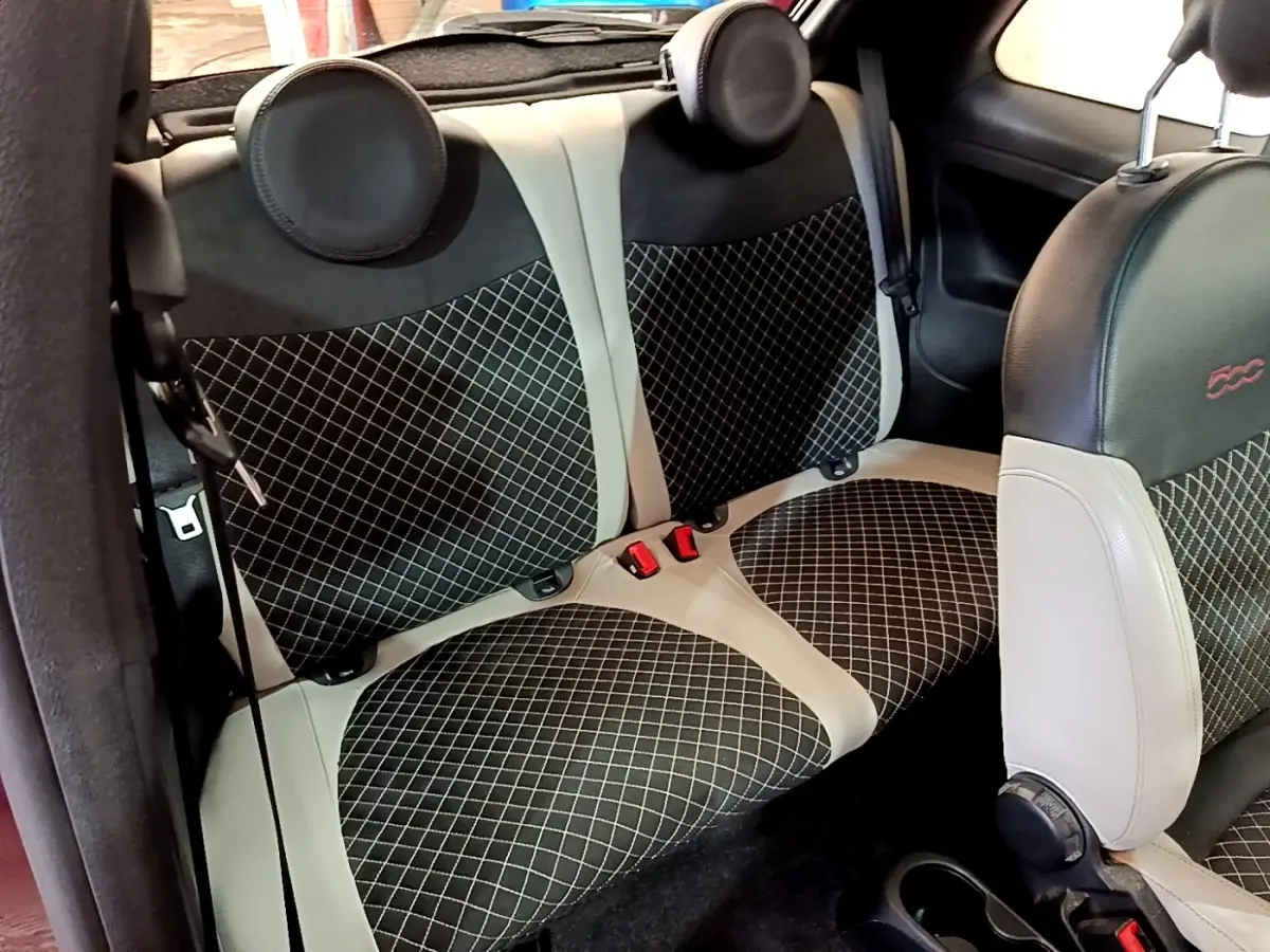 Vue intérieure sur la banquette arrière et siège avant de la FIAT 500 1.0 rouge avec sellerie noire et beige à motifs losanges.