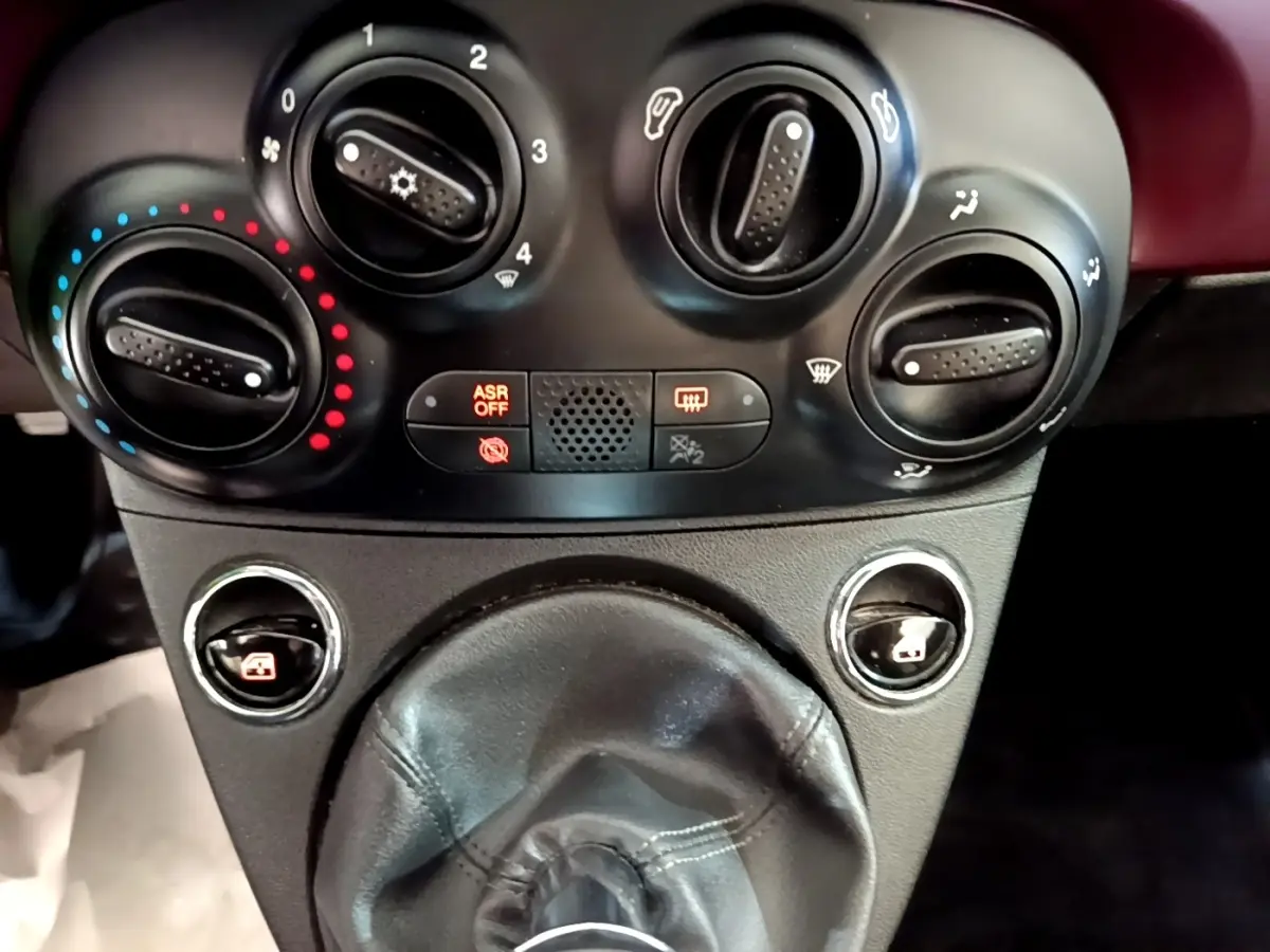 Gros plan sur les commandes de climatisation et le levier de vitesse cuir noir de la FIAT 500 rouge, version 1.0 70ch BSG Star.