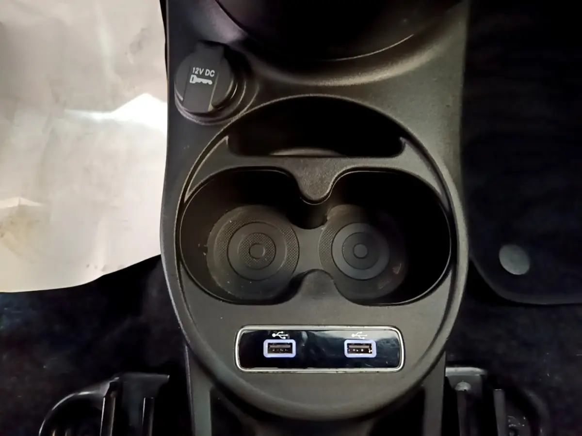 Vue rapprochée du porte-gobelets noir avec deux ports USB et prise 12V dans une FIAT 500 rouge.