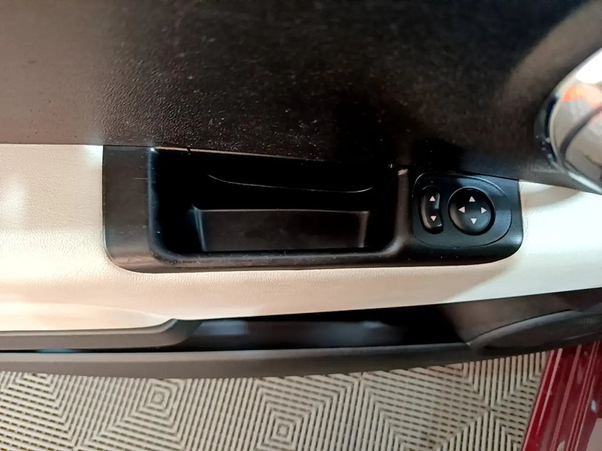 Détail de la commande des rétroviseurs sur la porte côté conducteur d'une FIAT 500 rouge.