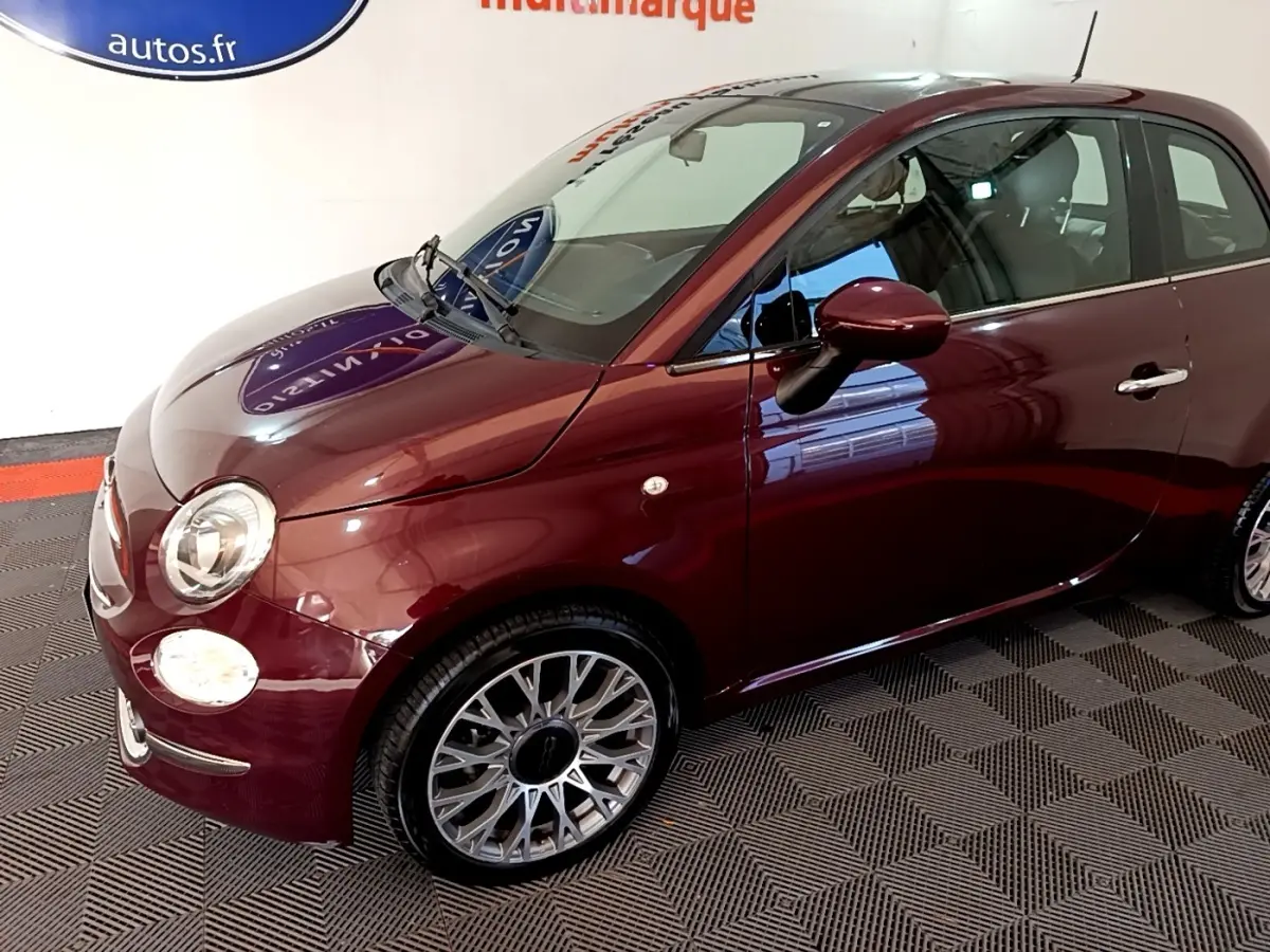 Vue 3/4 avant droit d'une FIAT 500 rouge brillant avec jantes alliage et rétroviseur assorti.