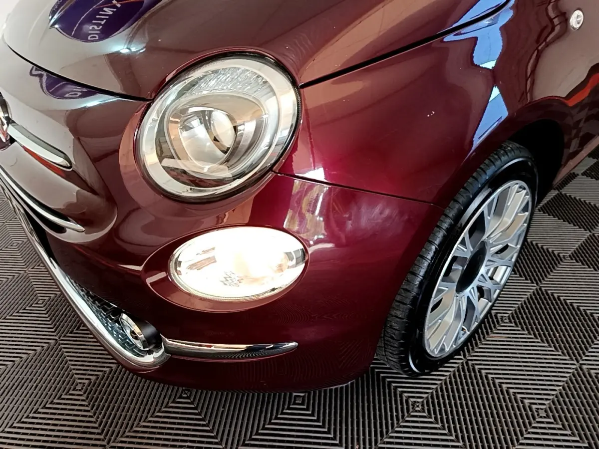 Gros plan sur l'avant droit de la FIAT 500 rouge, mettant en valeur le phare rond et la jante alu design.