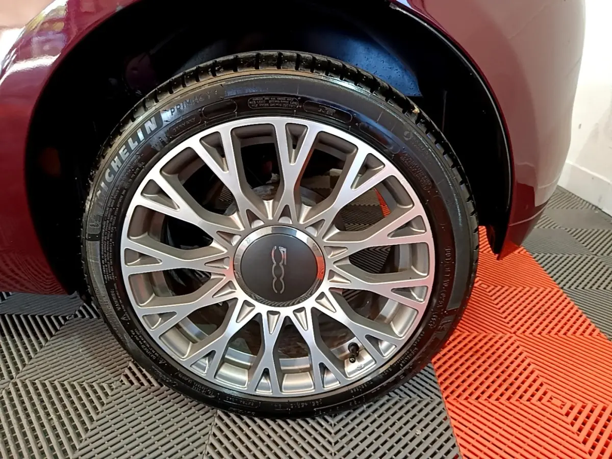 Gros plan sur la roue avant droite rouge de la FIAT 500 1.0 70ch BSG Star avec jante alliage argentée à multiples branches.