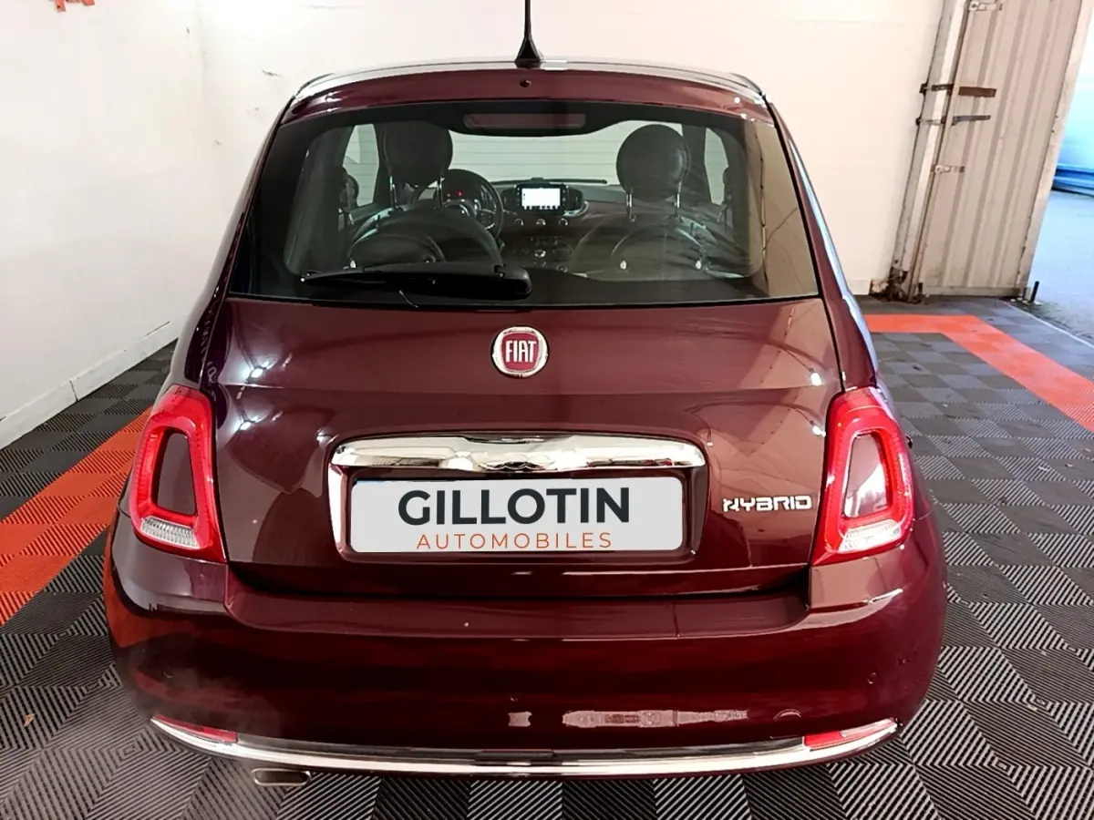 Vue arrière d'une Fiat 500 rouge hybride, avec logo FIAT et badge Hybrid visibles sur le coffre.