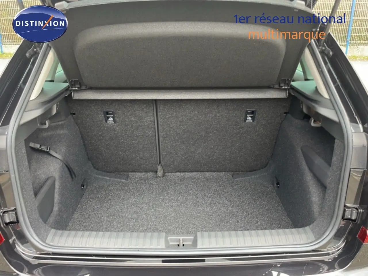 Coffre ouvert vu de l'arrière d'un Skoda Kamiq noir magique métal, montrant l'espace de chargement et la moquette grise.