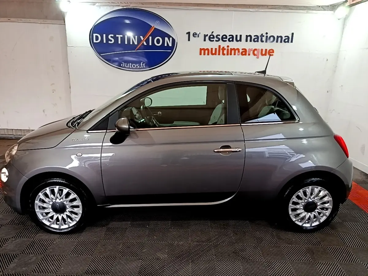 Profil latéral droit d'une FIAT 500 Dolcevita hybride gris foncé avec jantes alliage et intérieur visible.