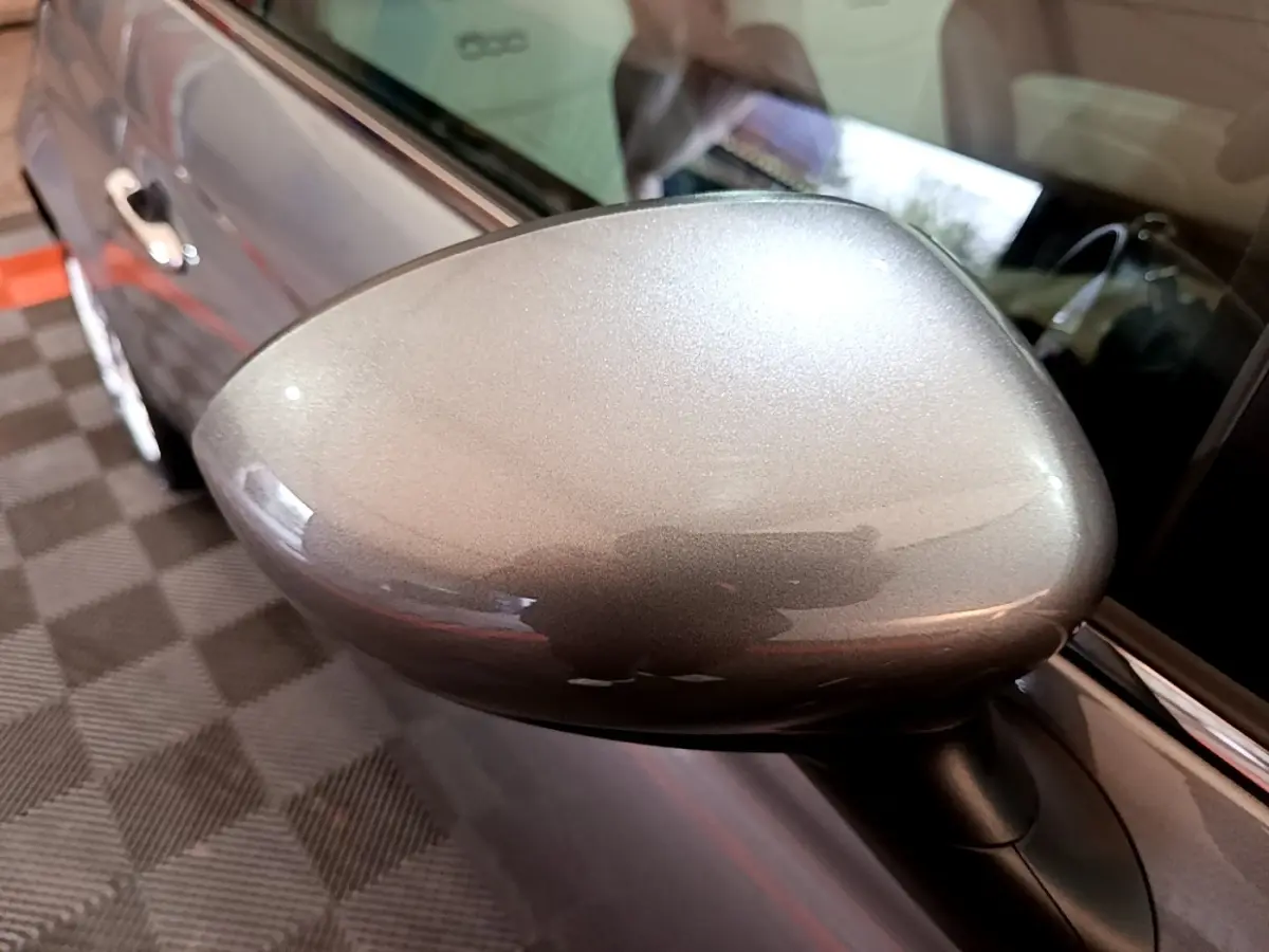 Rétroviseur gris foncé en gros plan côté gauche d’une FIAT 500 Hybrid 2021, avec portière et intérieur partiellement visibles.