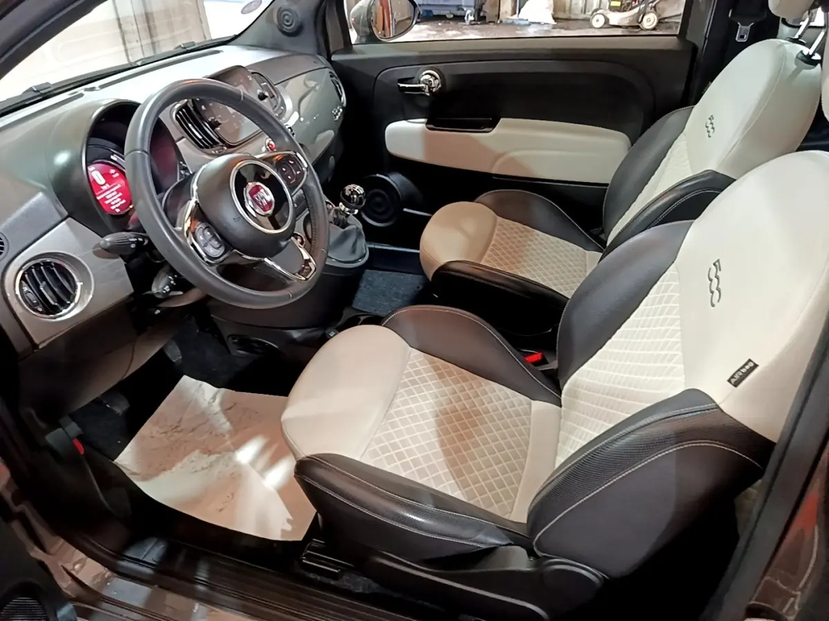 Vue intérieure côté conducteur de la Fiat 500 Hybrid 2021, sièges bicolores cuir noir et beige avec volant multifonctions.