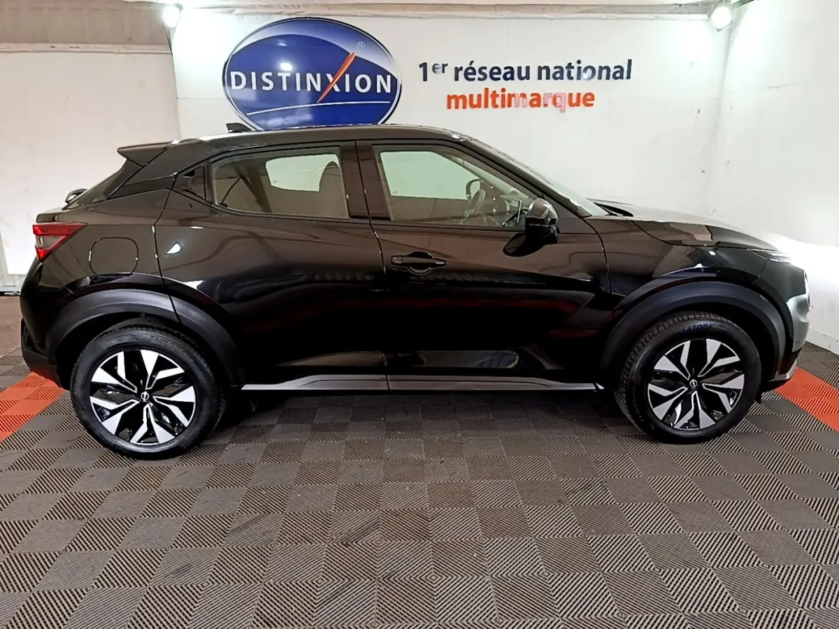Vue de profil côté gauche d'un Nissan Juke noir 2023 avec jantes alliage bicolores et poignées de porte intégrées.
