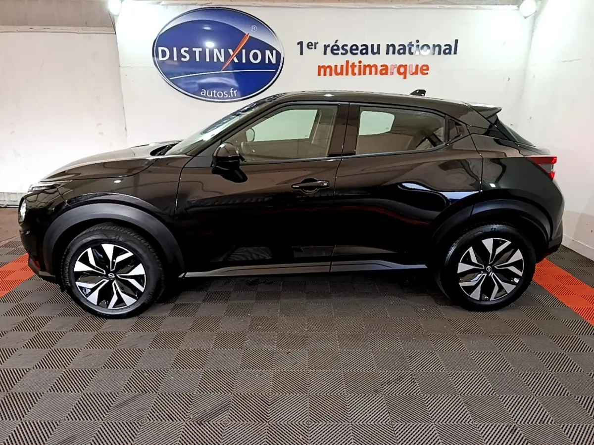 Profil droit du Nissan Juke noir 2023 DIG-T 114 BVM6 Acenta, avec jantes alliage bicolores et poignées de porte ton caisse.