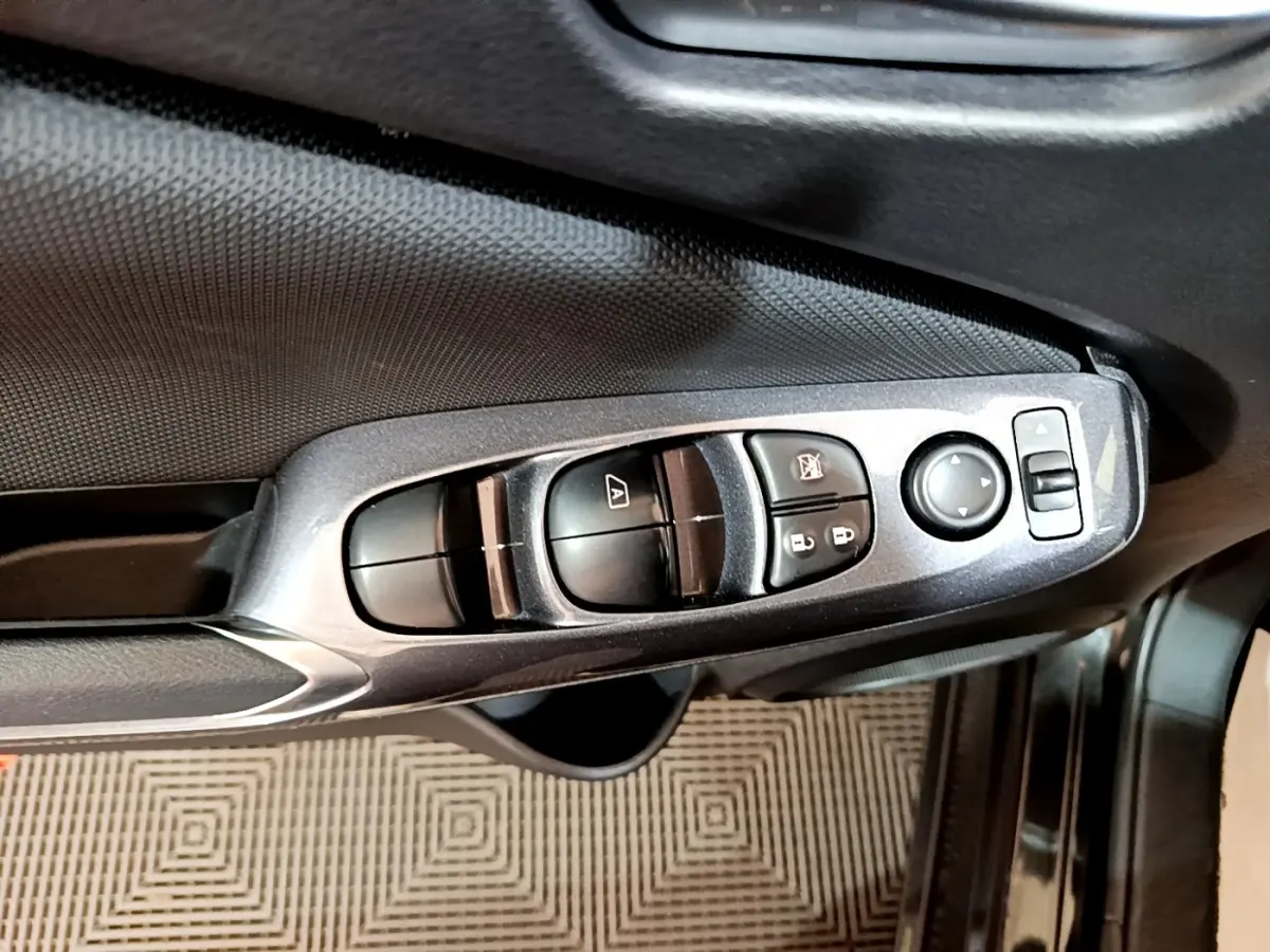 Gros plan sur les commandes de lève-vitres et rétroviseurs côté conducteur d’un Nissan Juke noir 2023.