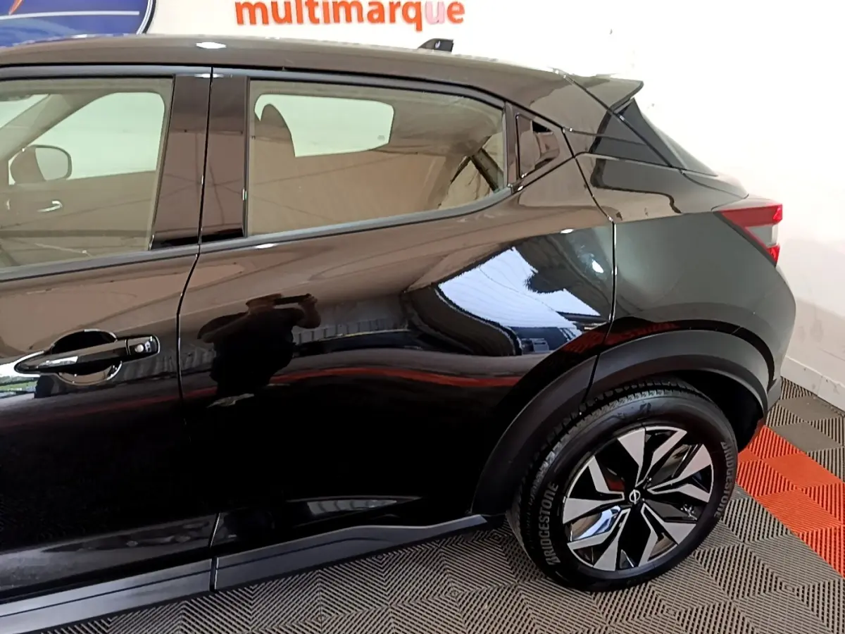 Vue latérale droite du Nissan Juke noir 2023, mettant en valeur la porte arrière et la roue avec jante design bicolore.