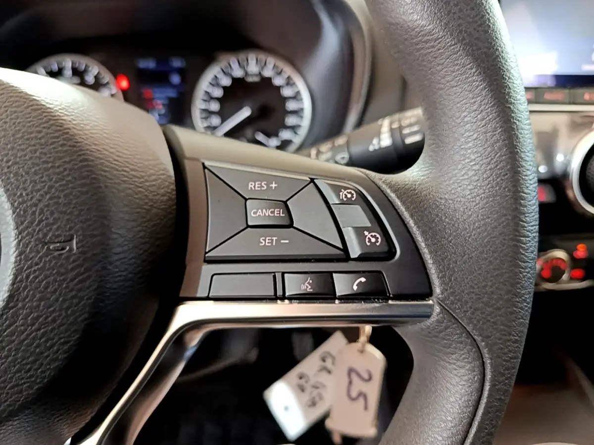 Gros plan sur le côté droit du volant noir du Nissan Juke 2023 avec commandes du régulateur de vitesse et téléphone.