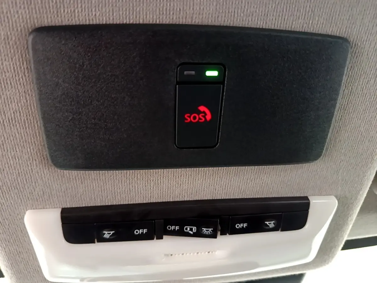 Bouton SOS rouge éclairé sur panneau de plafond gris clair dans l'habitacle du Nissan Juke noir 2023.