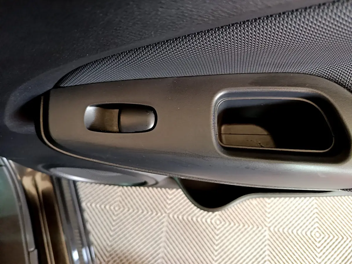 Gros plan sur la poignée intérieure de porte côté conducteur du Nissan Juke noir 2023, avec bouton de verrouillage.