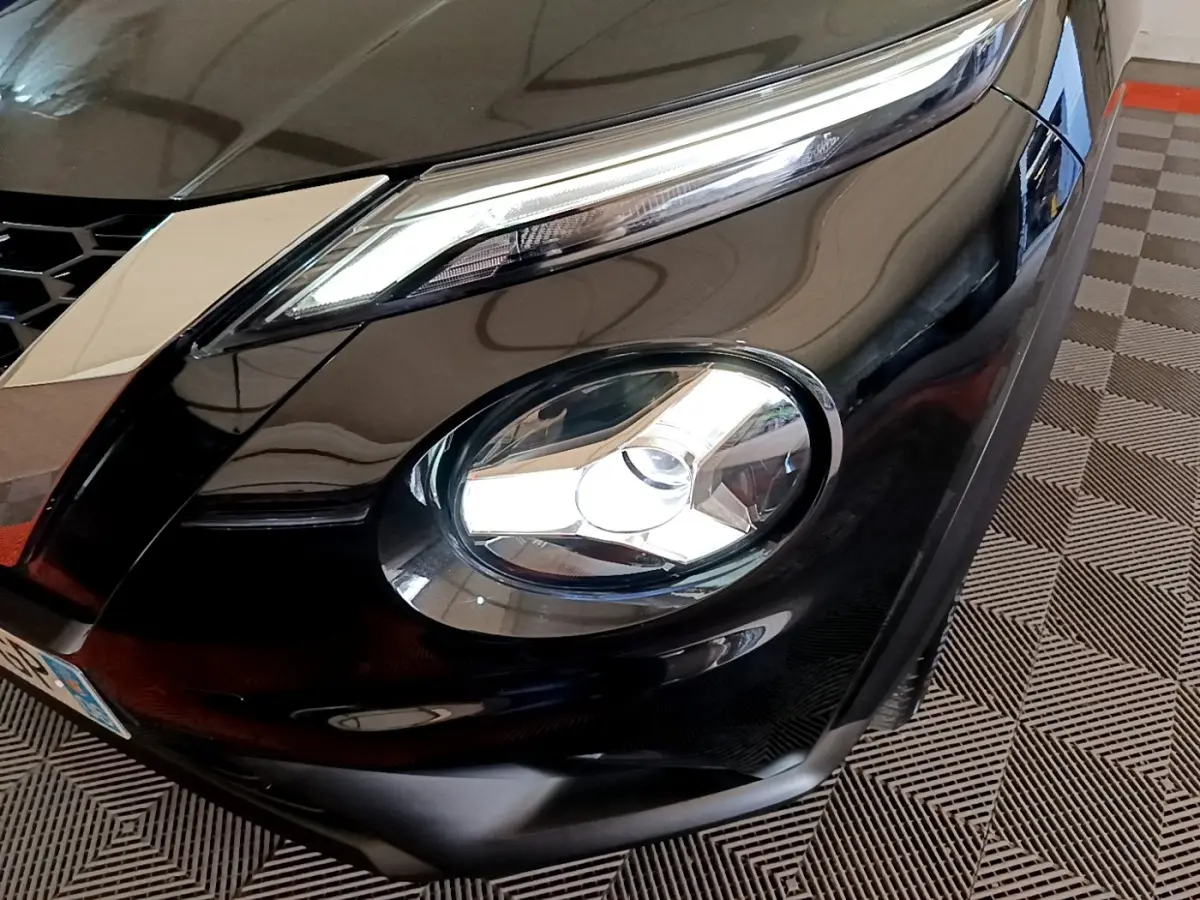 Gros plan sur le phare avant droit du Nissan Juke noir 2023, mettant en valeur ses feux LED et la calandre.