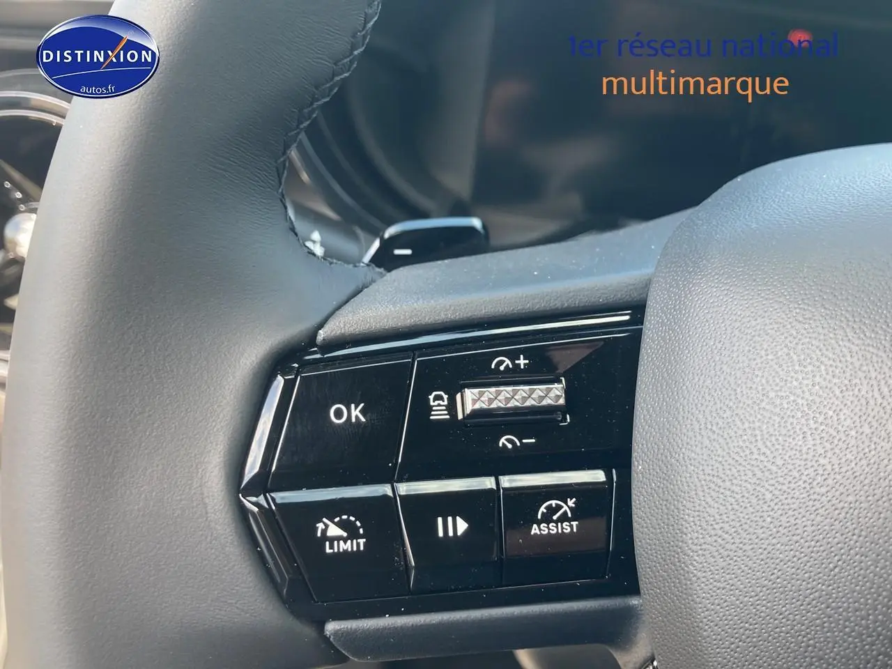 Gros plan sur les commandes au volant à gauche de l'Alfa Romeo Junior 1.2 hybride grise, montrant les boutons d'assistance et de régulation.