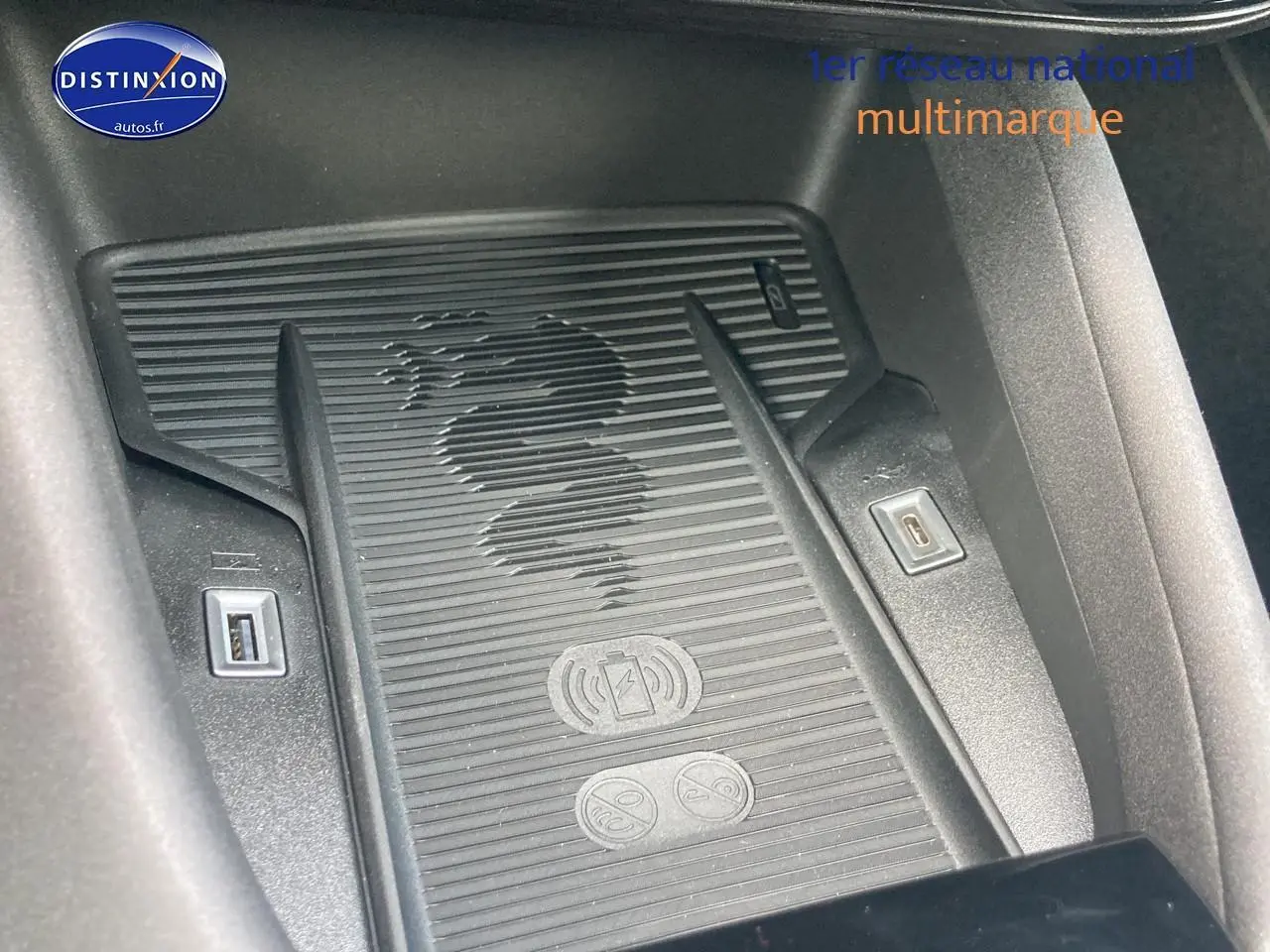 Gros plan sur le chargeur à induction avec logo serpent Alfa Romeo, entouré de ports USB dans l'habitacle gris.