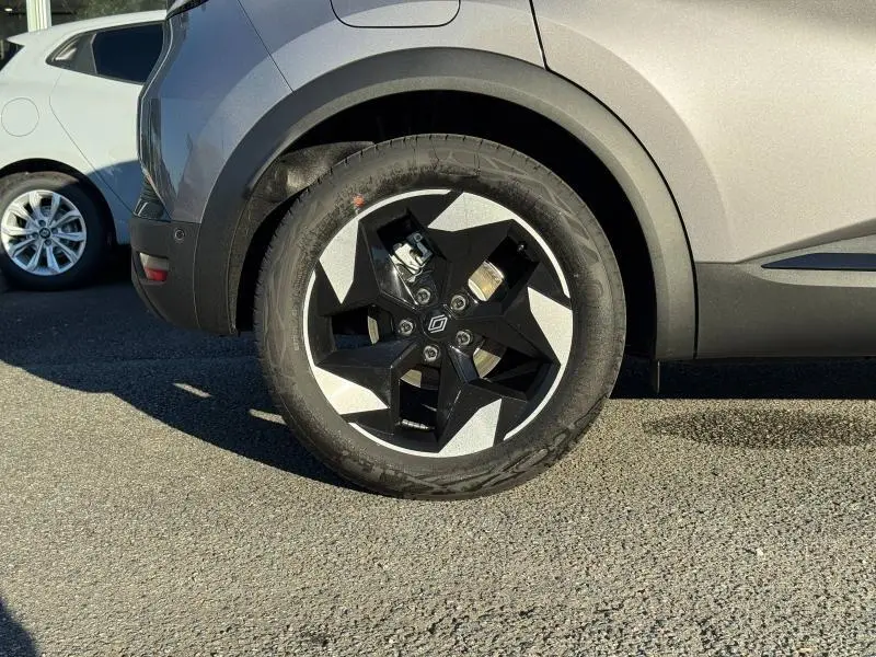 Gros plan sur la roue arrière droite avec jante noire et argent du Renault Captur 2025 rouge Flamme.