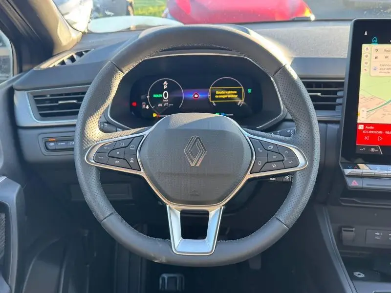 Vue frontale du volant multifonction noir du Renault Captur 2025 avec tableau de bord numérique et écran tactile latéral.