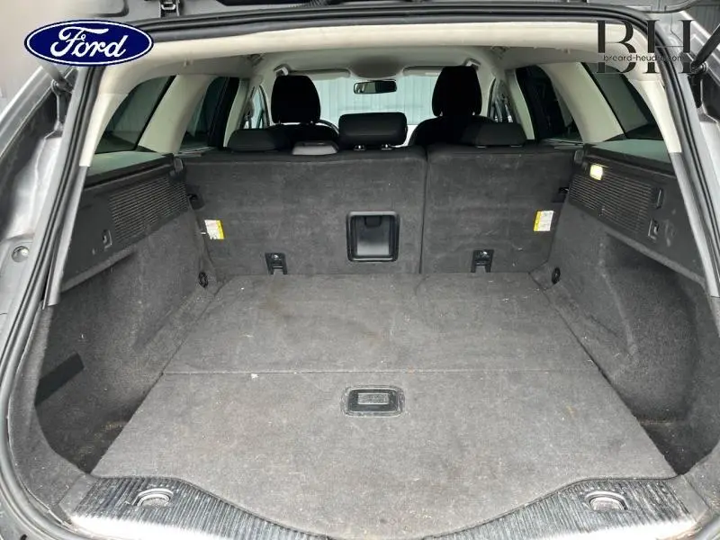 Vue du coffre ouvert d'une Ford Mondeo SW gris Magnetic, montrant l'espace de chargement et la banquette arrière rabattue.