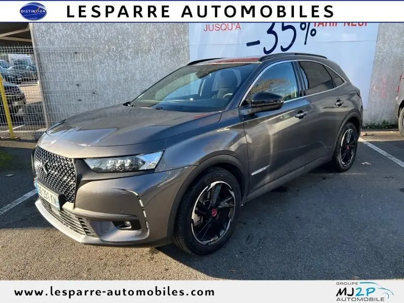 DS7 Crossback E-TENSE gris en 3/4 avant droit, soulignant sa calandre distinctive et ses jantes noires brillantes.